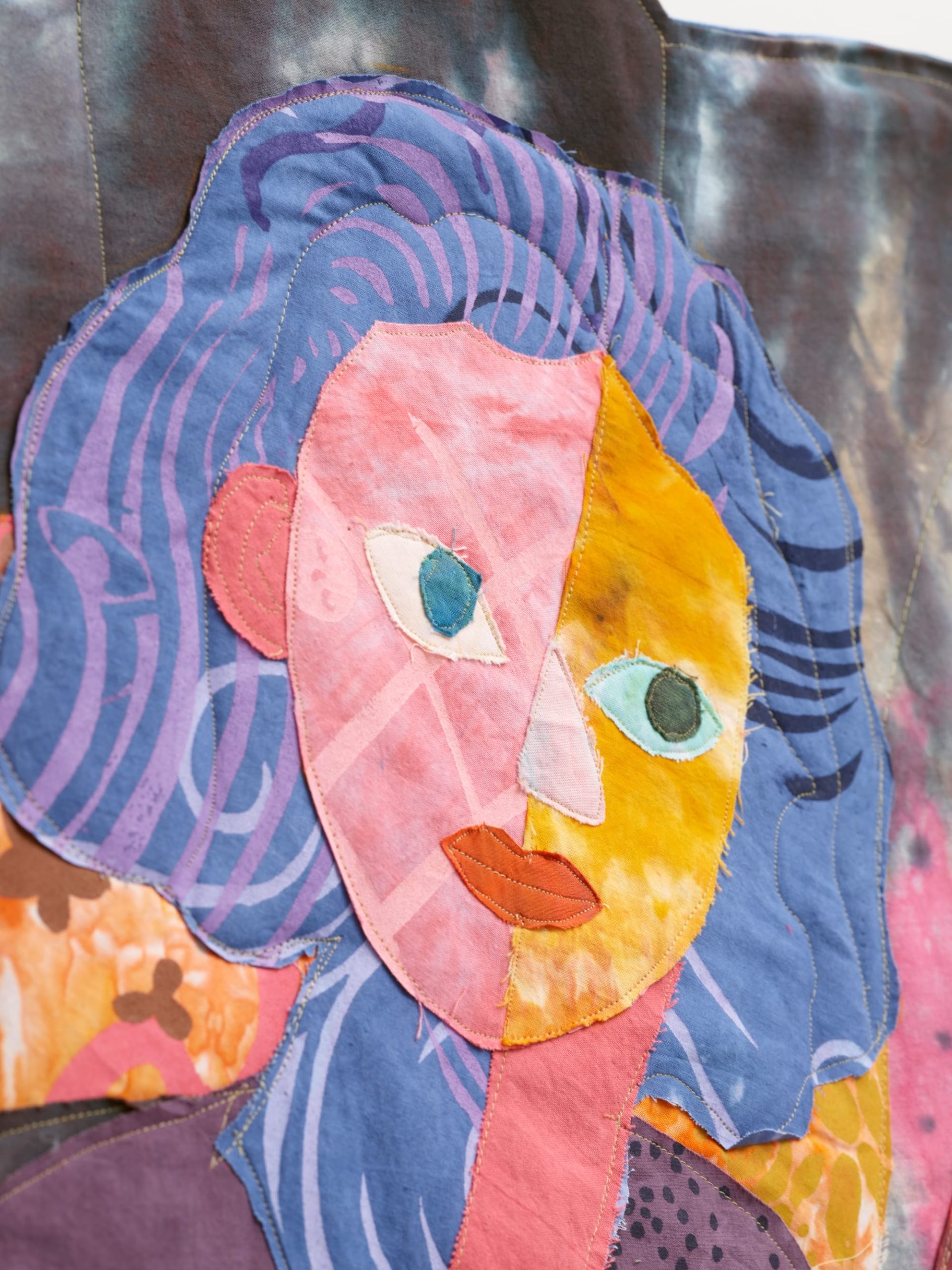 detail of a textile portrait of a woman in vivid, patterned fabrics