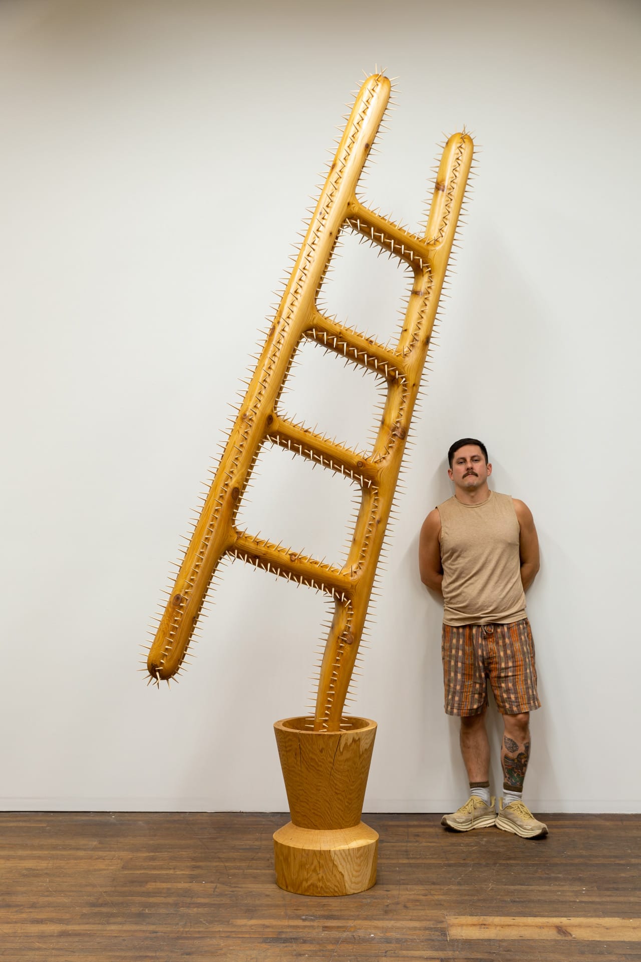 Raul De Lara next to his sculpture of a ladder growing from a pot