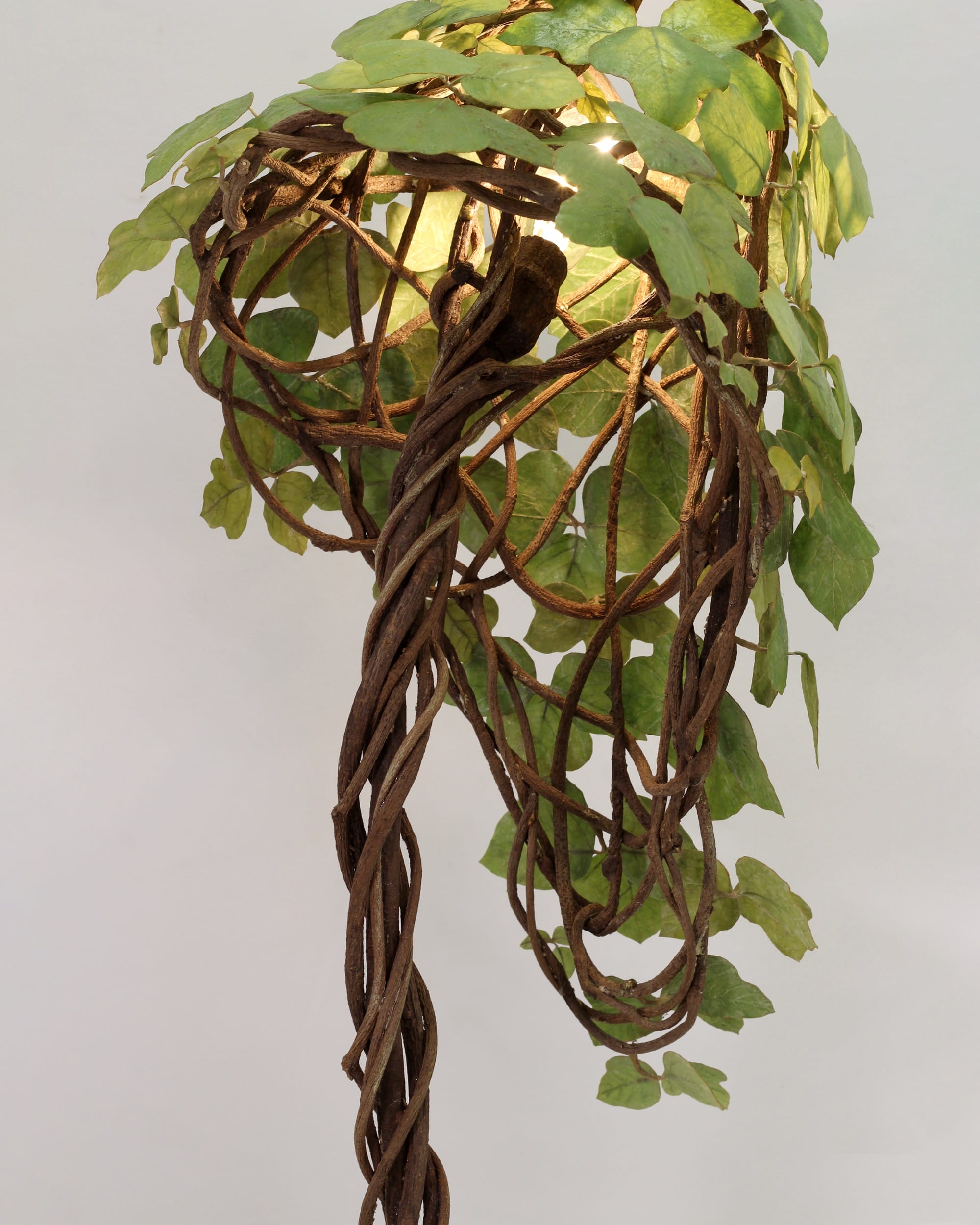 a detail image of a floor lamp with kudzu leaves and roots covering the base and shade by Joyce Lin