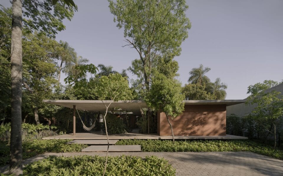The exterior of a contemporary concrete, glass, and steel home amid trees and tropical plants