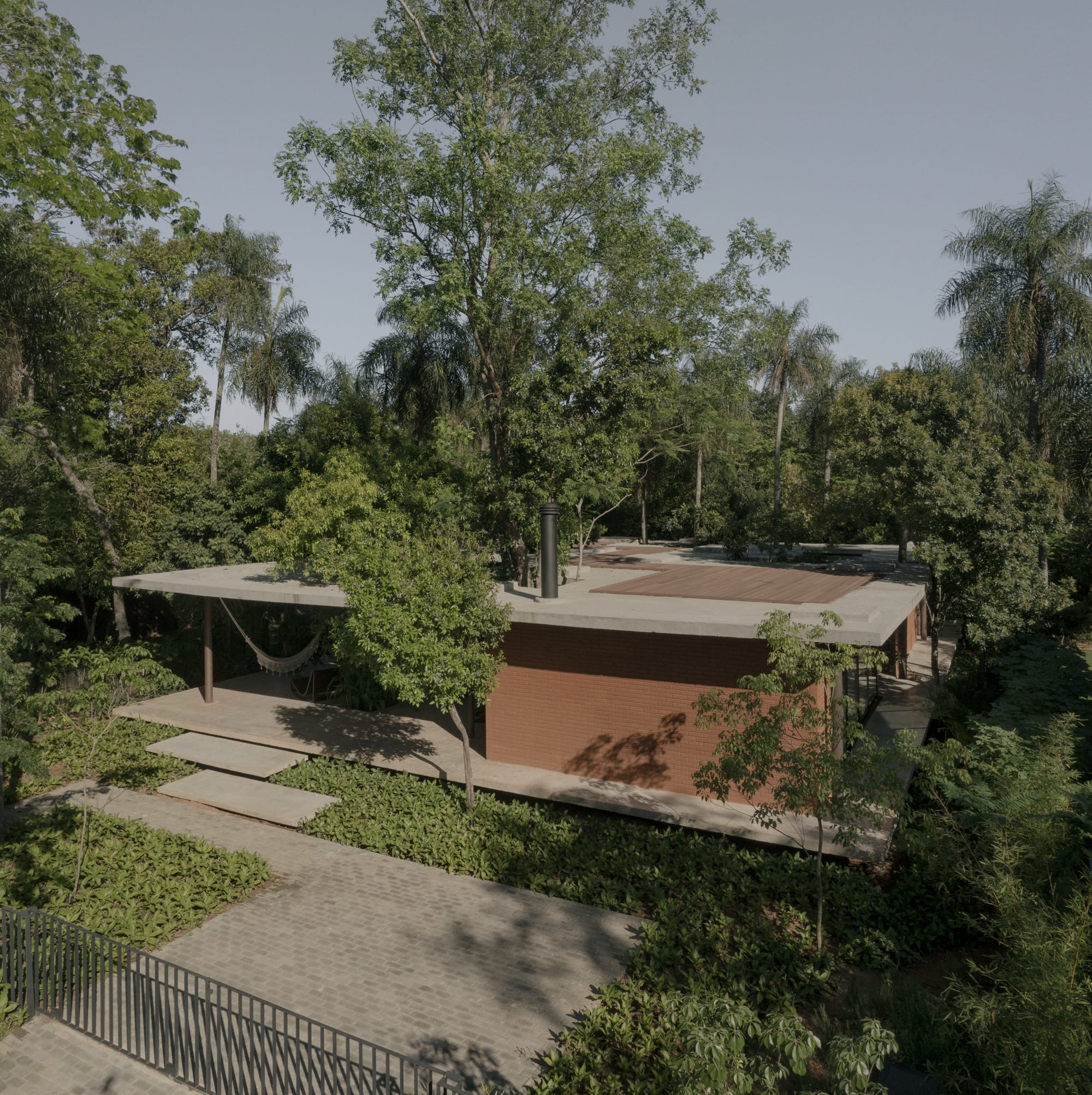 An aerial view of the exterior of a contemporary concrete, glass, and steel home amid trees and tropical plants